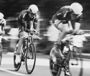 Drie wielrenners in helmen rijden dicht achter elkaar op een parcours