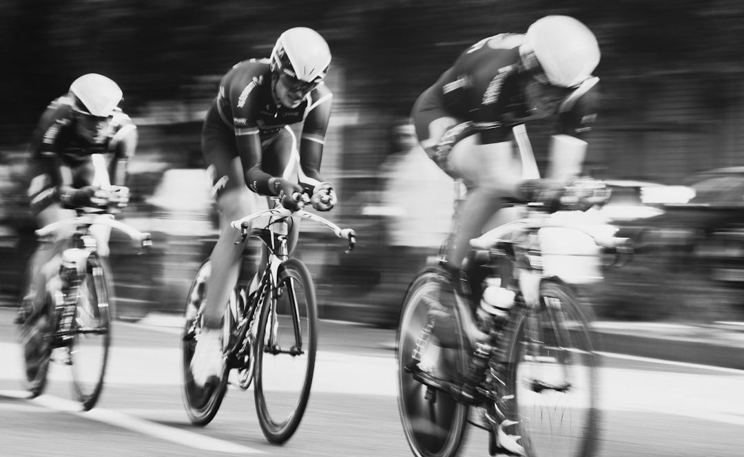 Drie wielrenners in helmen rijden dicht achter elkaar op een parcours